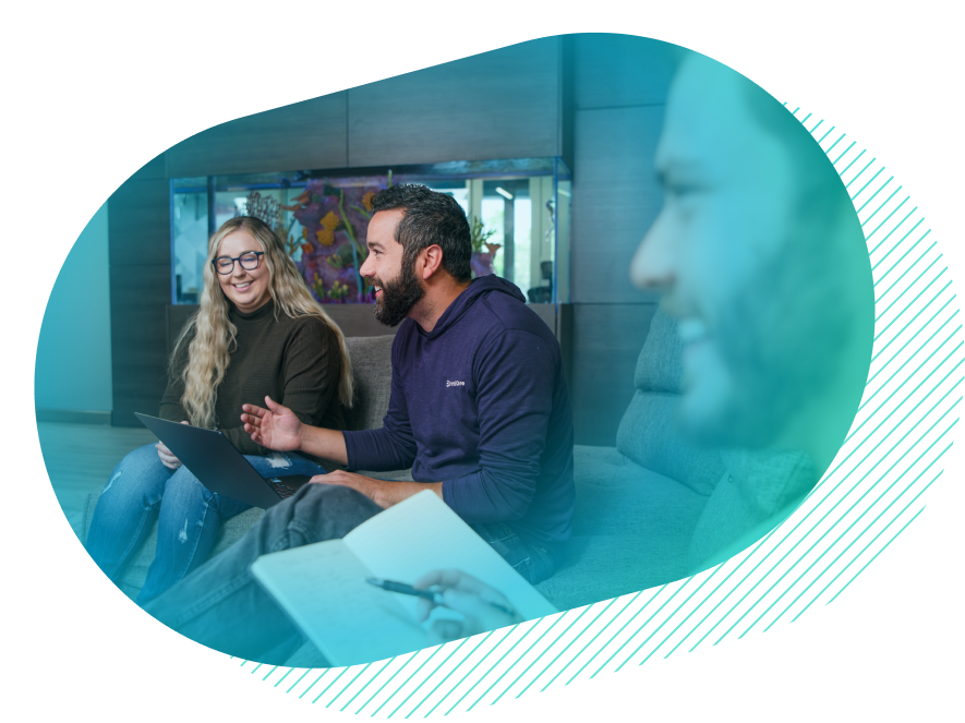 Co-workers have a meeting while sitting on couches in front of a fish tank